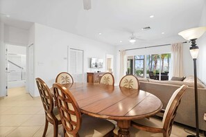 A dining area with a wooden table and chairs, a sofa, and a view of the outdoors. - Kaibo Yacht Club  2 Bdr Beachfront Condo Hot Tub and Pool (Rum Point)
