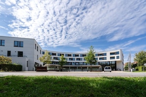 Ein modernes Gebäude mit einer gewölbten Fassade, zahlreichen Fenstern und einem überdachten Eingangsbereich.