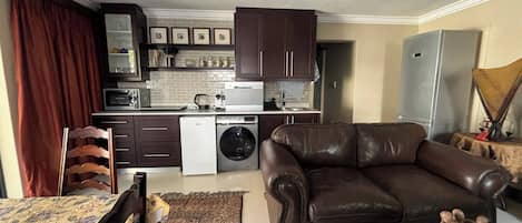 A modern kitchen with a dining area, a leather sofa, and a chandelier.