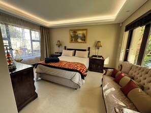 A hotel room with a bed, a sofa, a desk, and a window with curtains. - Guest suite Sunset Beach, Milnerton 85m2 (Milnerton)
