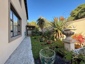 A modern building with a narrow concrete pathway leading to a covered patio area. - Guest suite Sunset Beach, Milnerton 85m2 (Milnerton)