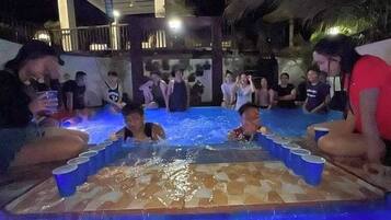 A group of people around a pool with a tiled floor and blue lighting.