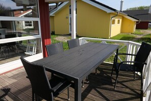 Eine Terrasse mit Tisch und Stühlen mit Blick auf ein gelbes Gebäude und eine grüne Rasenfläche.