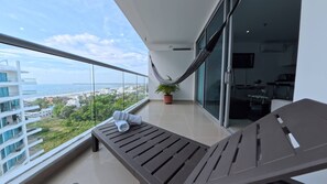A balcony with a view of the ocean and cityscape, a hammock, a potted plant, and a lounge chair. - Beautifull Condo Apartament with sea view Morros Sonesta (Cartagena)