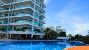 A multi-story hotel with a swimming pool, palm trees, and a clear sky. - Beautifull Condo Apartament with sea view Morros Sonesta (Cartagena)