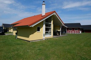 A yellow building with a red roof, a chimney, and a covered outdoor seating area. - Grobenbrode Haven mit gemütlichem Kamin (Großenbrode)