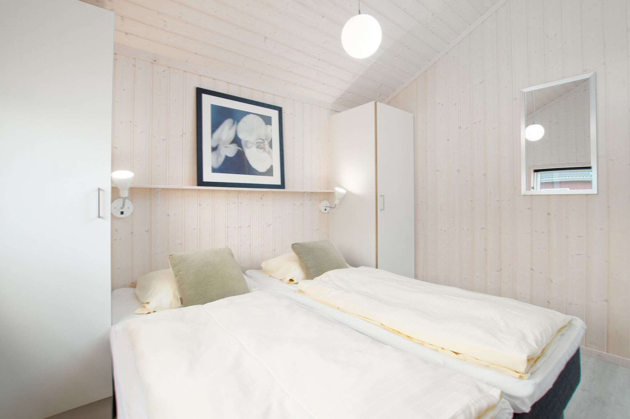 Quarto com duas camas, um quadro na parede e um espelho.