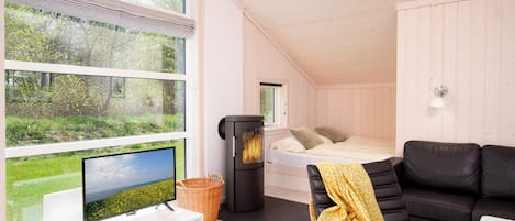 Una habitación acogedora con una cama, televisión, chimenea y ventana con vistas a zonas verdes.