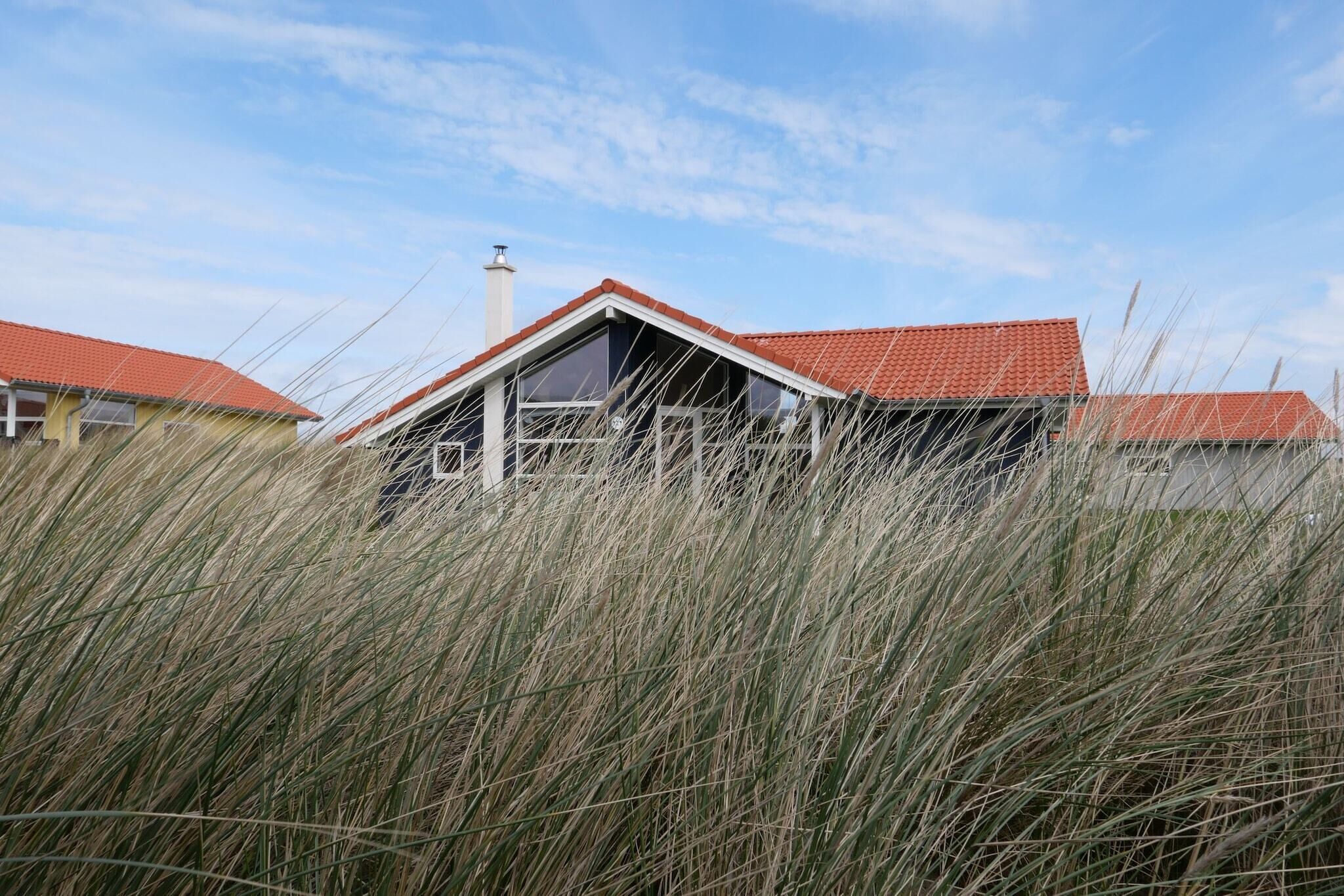 A house with a red roof, surrounded by tall grass.