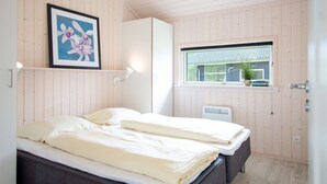 Ein Schlafzimmer mit einem Bett, einem gerahmten Bild, einem Fenster und einer Heizung.