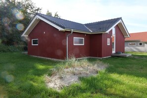 Een rood gebouw met schuin dak, klein raam en een deur.