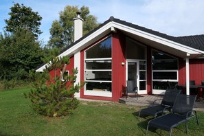 A red building with a large glass window, a chimney, and a small tree in the foreground. - Grobenbrode Dune-Side Spa Retreat (Großenbrode)