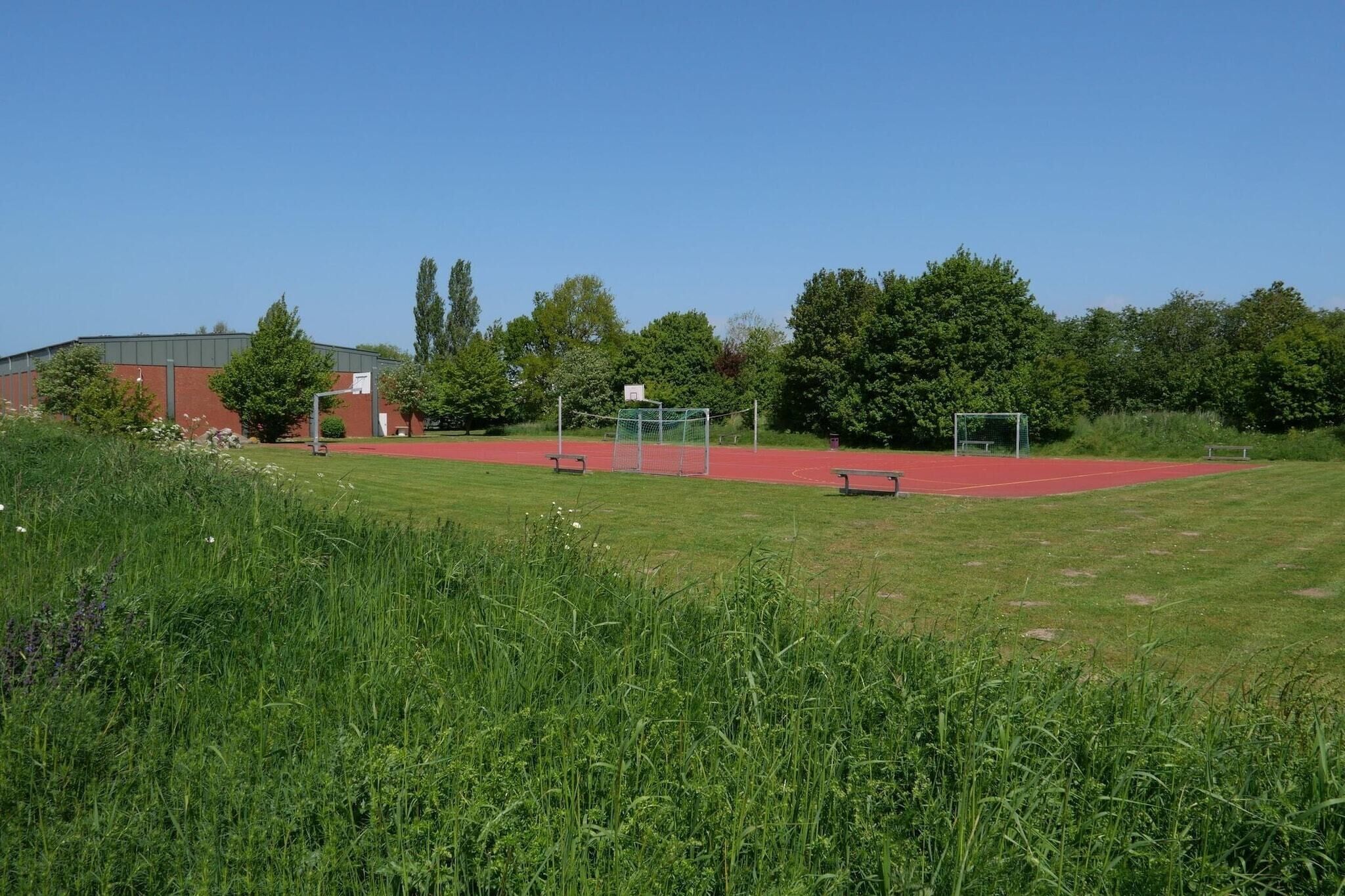 A sports field with a running track, a basketball court, and a soccer goal.