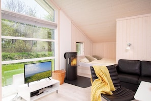 Ein gemütliches Zimmer mit Bett, Fernseher, Kamin und Blick auf Grünflächen.