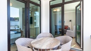 A modern balcony with glass doors, a round table, and two chairs. - Apartment in Strand- und Parknähe (Travemünde)
