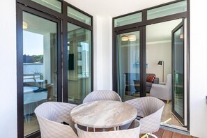 A modern balcony with glass doors, a round table, and two chairs. - Apartment in Strand- und Parknähe (Travemünde)