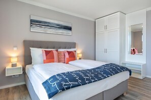 Un dormitorio moderno con cama, lámparas de noche, armario y un cuadro en la pared.