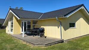 Een gelijkvloers huis met een overdekte patio, een barbecue en een raam.