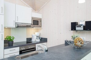 A modern kitchen with stainless steel appliances, a coffee maker, and a pineapple on the counter. - Spa-Ferienhaus mit zwei Flügeln (Großenbrode)