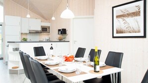 Eine moderne Küche mit weißen Schränken, einer Mikrowelle und einem Essbereich mit einem Tisch für sechs Personen.