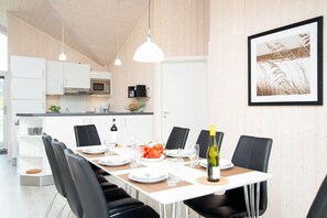 Eine moderne Küche mit weißen Schränken, einer Mikrowelle und einem Essbereich mit einem Tisch für sechs Personen.