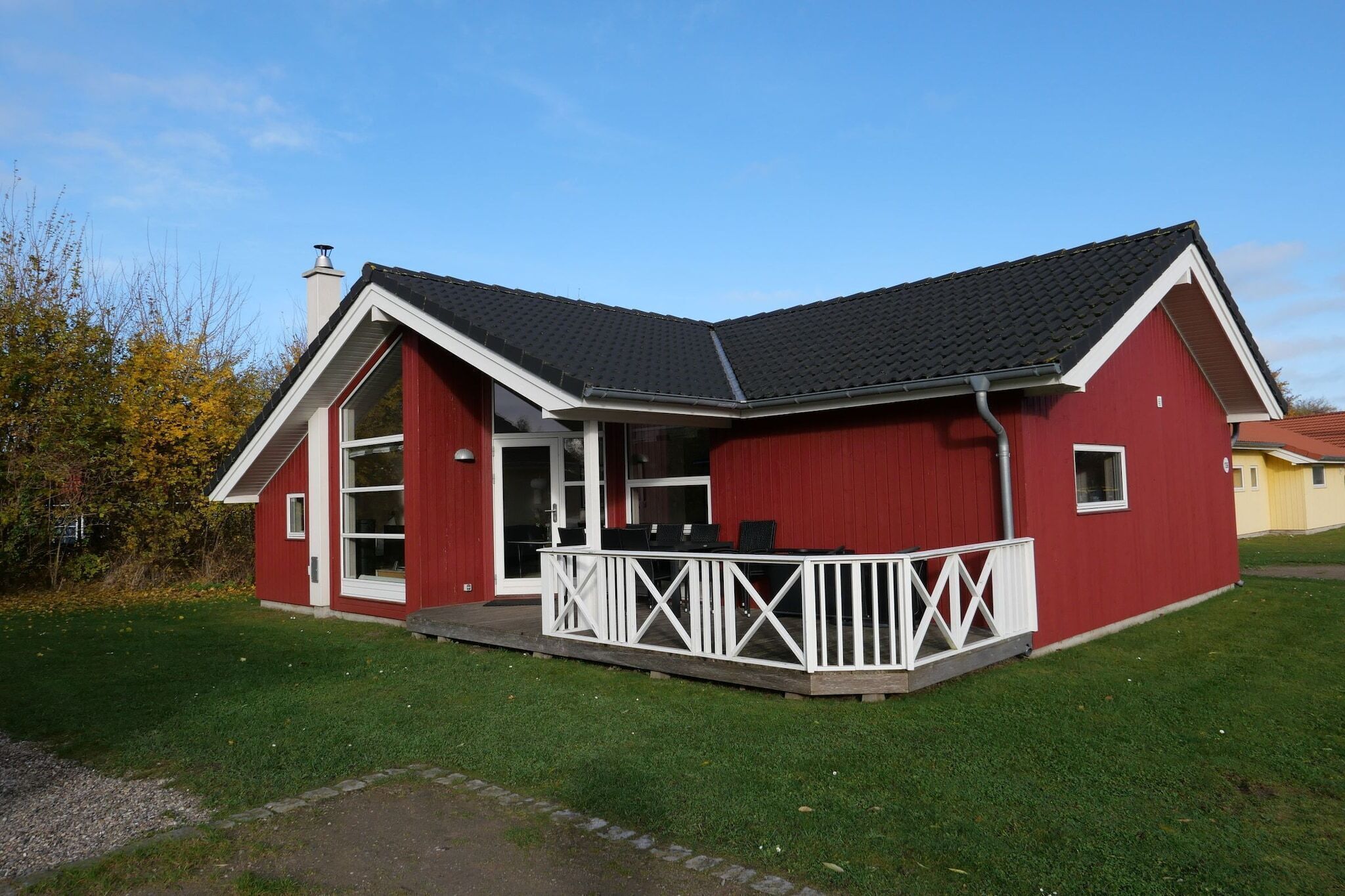 Un bâtiment rouge avec un porche blanc et un toit noir.