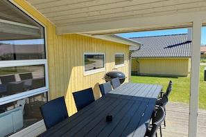 Eine Außenpatio-Terrasse mit Tisch, Stühlen, einem Grill und Blick auf eine Straße sowie Gebäude im Hintergrund.