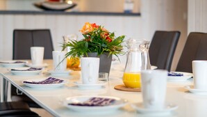 A breakfast table set with plates, cups, a pitcher of orange juice, and a floral centerpiece. - Grobenbrode Escape f ür 10 (Großenbrode)