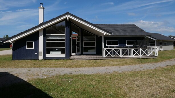 A modern two-story house with a sloped roof, a covered porch with white railings, and a chimney. - Grobenbrode Baltic Horizon Haven (Großenbrode)