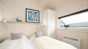A bedroom with a bed, a window, a radiator, and a framed picture on the wall. - Grobenbrode Baltic Horizon Haven (Großenbrode)