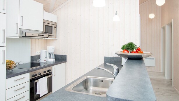 A modern kitchen with a built-in oven, microwave, and a stainless steel sink. - Grobenbrode Green Lawn Sanctuary (Großenbrode)