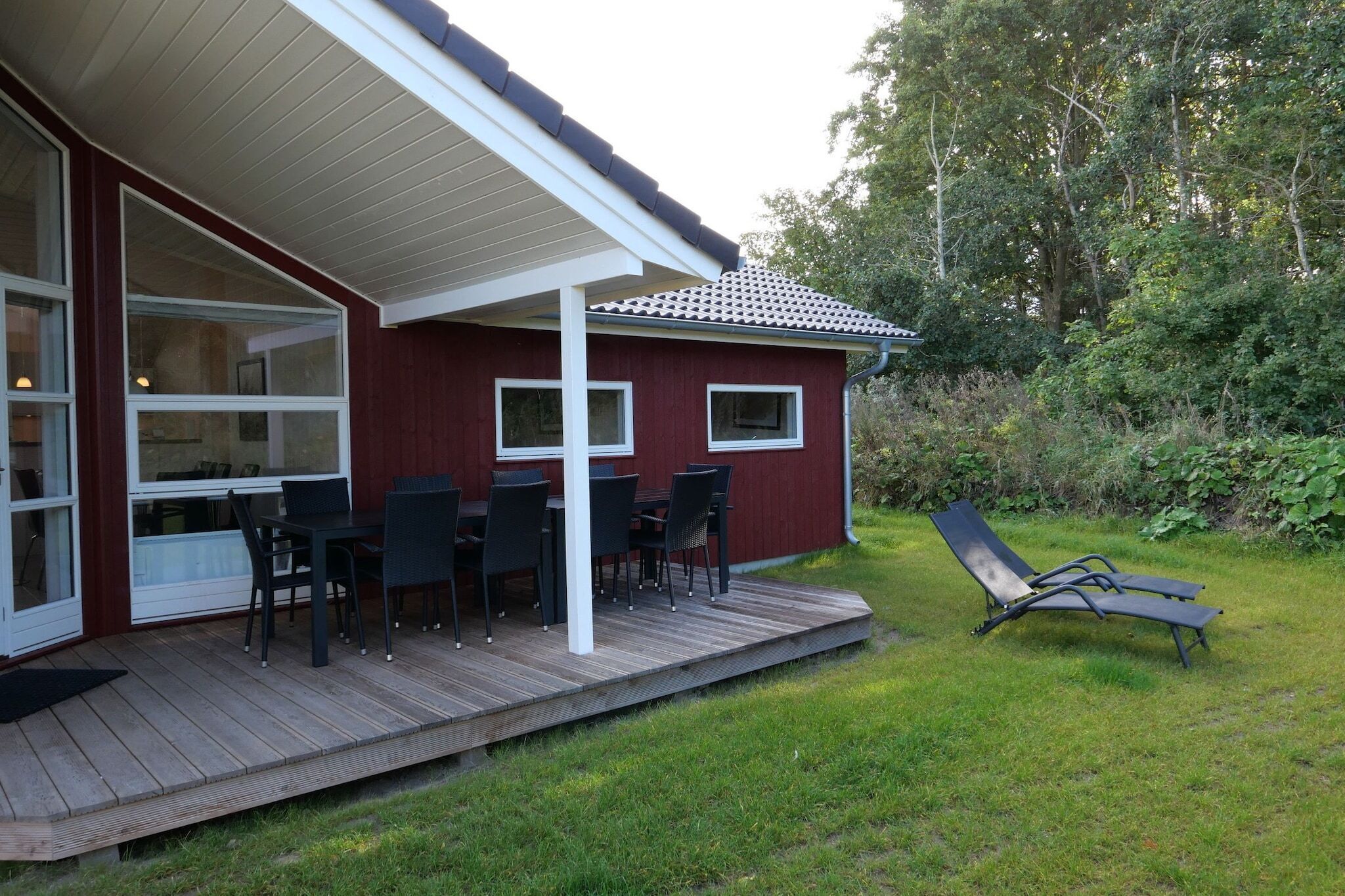 Un'area esterna coperta con tavolo e sedie, un patio e un prato.