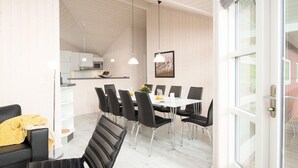 A modern kitchen with white cabinets, a microwave, and a dining area with a white table and black chairs. - Grobenbrode Green Lawn Sanctuary (Großenbrode)