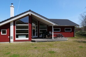 Ein rotes Gebäude mit einem großen Glasfenster, einer Veranda und einem Schornstein.