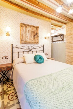 A bedroom with a bed, a nightstand, a wall-mounted lamp, and a wooden cabinet.