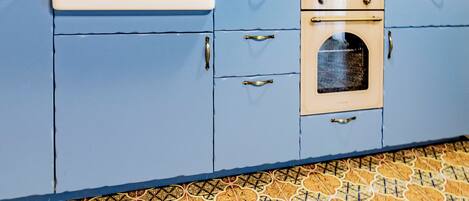 A kitchen with blue cabinets, a white sink, and a patterned tile floor.