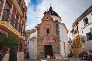 A narrow street with a church featuring a bell tower and a cross, flanked by buildings with balconies and a palm tree. - Refugi dels Somnis - "Antiguo Pincel" - Charming Tourism in Onda (Onda)