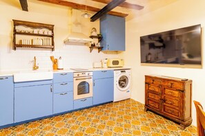 A compact kitchen with blue cabinets, a washing machine, a microwave, and a wooden cabinet. - Refugi dels Somnis - "Antiguo Pincel" - Charming Tourism in Onda (Onda)