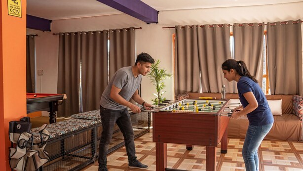 A room with a foosball table, a pool table, and a sofa.