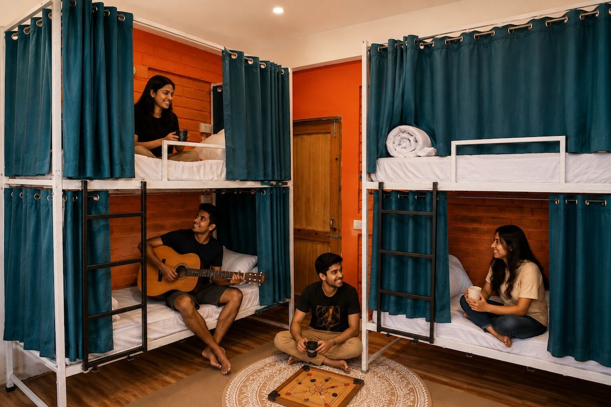 A dormitory room with bunk beds, a wooden floor, and a foosball table.