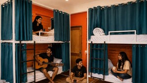 A dormitory room with bunk beds, a wooden floor, and a foosball table.