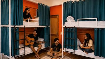 Ein Schlafsaalzimmer mit Etagenbetten, Holzboden und einem Kicker.