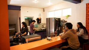 A modern kitchen with a central island, a refrigerator, and a window. - Loopin Mcleodganj  (Dharamshala)