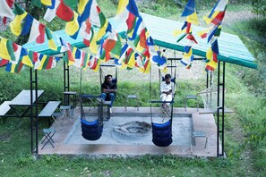 Un espacio de estar al aire libre techado, con mesas, sillas, una hamaca y un columpio.