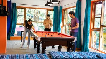 A pool table in a room with large windows and curtains.