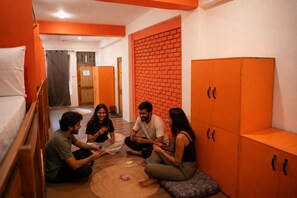 Un grupo de personas sentadas en el suelo de una habitación con paredes naranjas y muebles de madera.