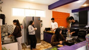 A modern kitchen with a refrigerator, sink, and a brick accent wall. - Loopin Mcleodganj  (Dharamshala)