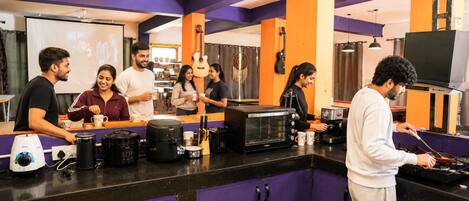 Un coin cuisine équipé d’une machine à café, d’un four à micro-ondes et où une personne est en train de cuisiner.