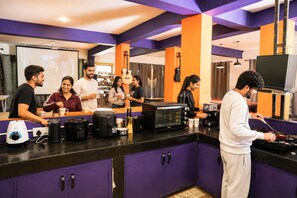 Un área de cocina con cafetera, microondas y una persona cocinando.