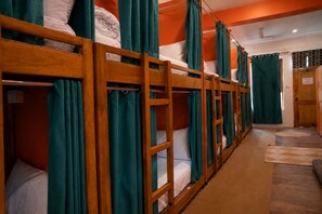 Unos literas con cortinas, suelo de madera y una puerta al fondo.